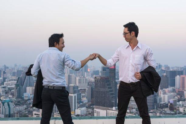 公司同事之间的团队合作，专业夫妇商人在城市景观背景下的傍晚时间，商业成功的概念图片下载