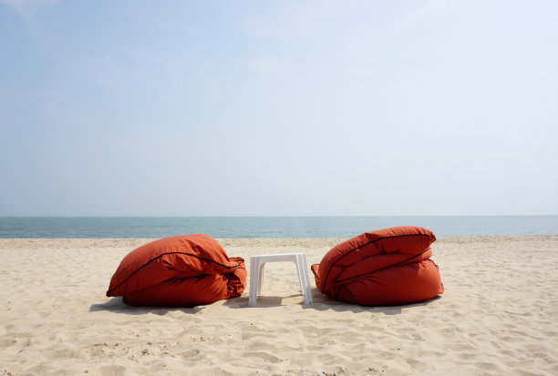 橙色的沙滩床和白色的塑料桌子图片下载