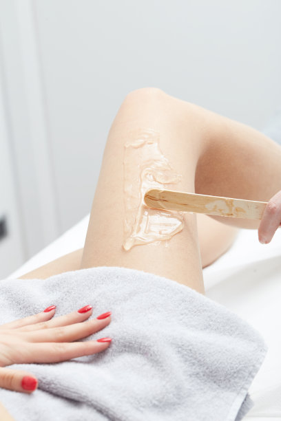 美容师给脱毛蜡处理女人的大腿图片下载
