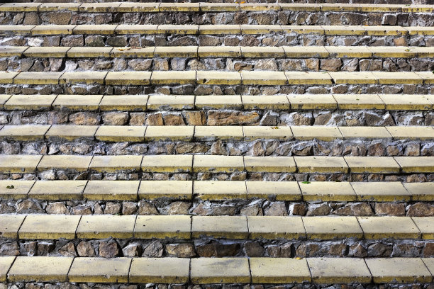 一个梯子的水平台阶，以黄色的砖和花岗岩粗糙的石头为背景图片下载