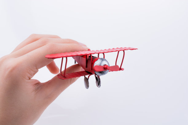 手里拿着白色背景上的玩具飞机图片下载