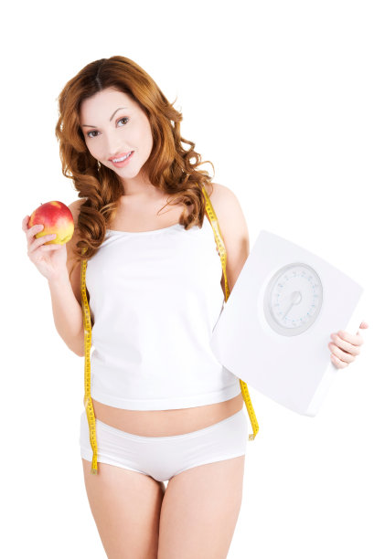 漂亮苗条的女人，带着苹果，秤和卷尺。图片下载