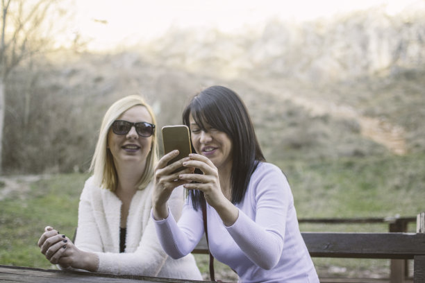 两个快乐的姐妹在智能手机上分享社交媒体图片下载