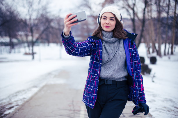 年轻女子在公园里用智能手机自拍图片下载