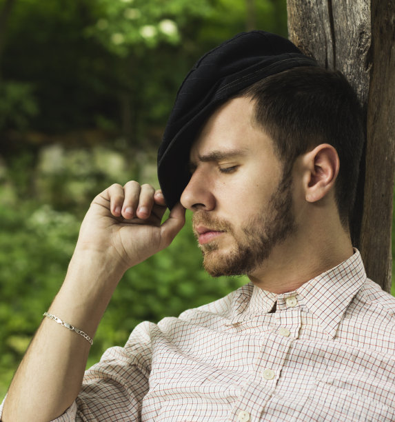 戴帽子的年轻成年男子在户外休息图片下载