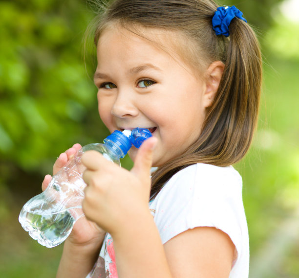 可爱的女孩用一个塑料瓶喝水图片下载