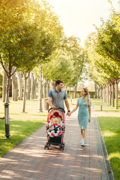 一对年轻的夫妇带着婴儿车里的小女孩散步图片下载