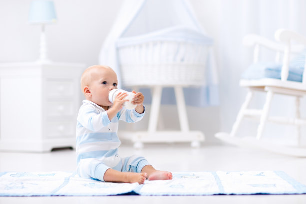 男婴在阳光明媚的托儿所喝牛奶素材图片