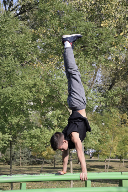 健康的年轻人。在吧台上倒立。街头运动。图片下载