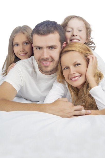 家人微笑着躺在铺着白色亚麻布的床上图片下载