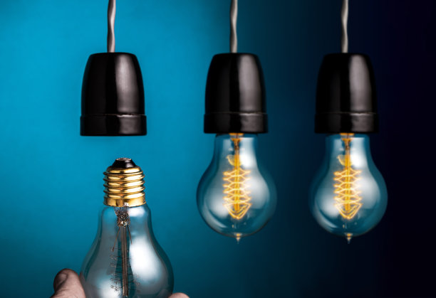 手工更换一个古董爱迪生风格的灯丝灯泡在深蓝色的背景。图片下载