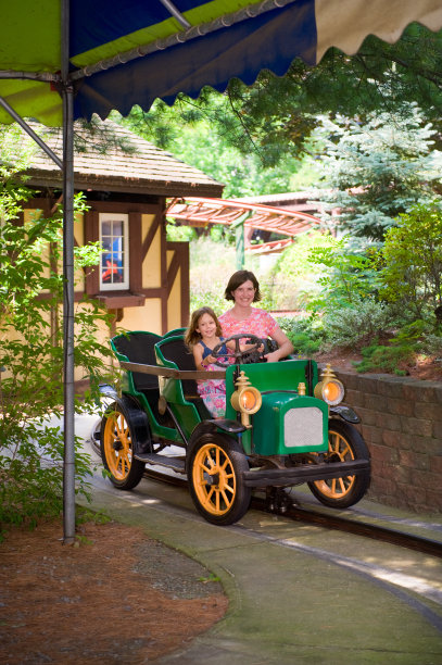 母亲和女儿在游乐园:小女孩开车图片下载