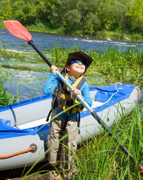 快乐的小男孩拿着皮划艇附近的桨图片下载