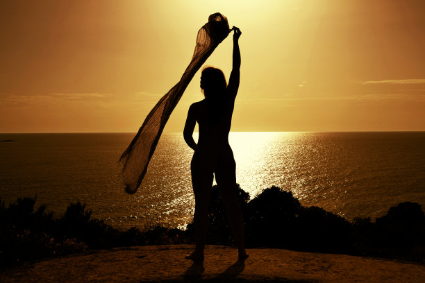 日落时戴着围巾的漂亮年轻女子。图片下载