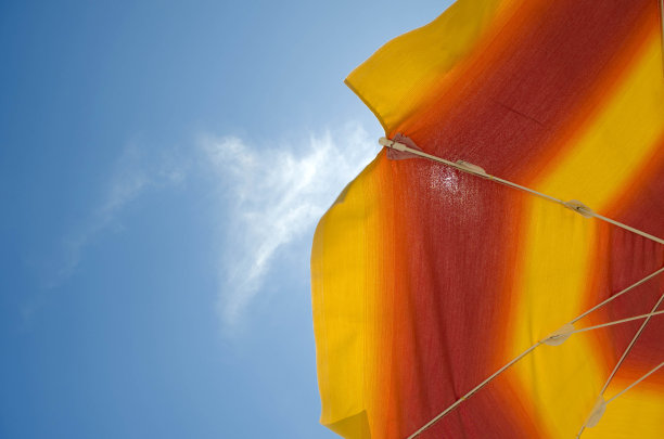 蓝色天空上的橙色太阳伞。夏天的背景。图片下载