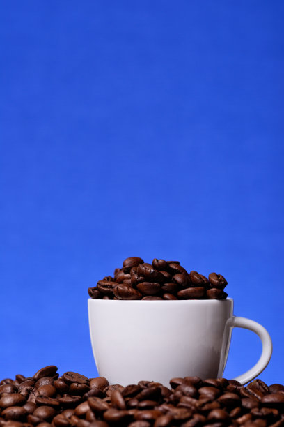 蓝色背景上有咖啡豆的白色杯子图片下载