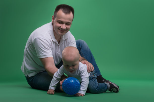 父亲和蹒跚学步的儿子在玩球图片下载
