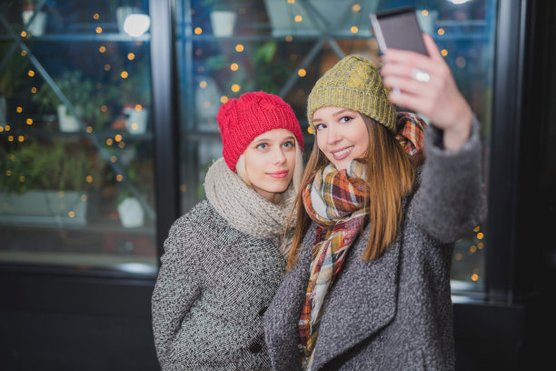 两个美丽快乐的女孩在散景背景上自拍图片下载