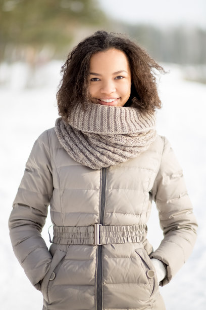 积极的女人穿着暖和的夹克站在森林里图片下载
