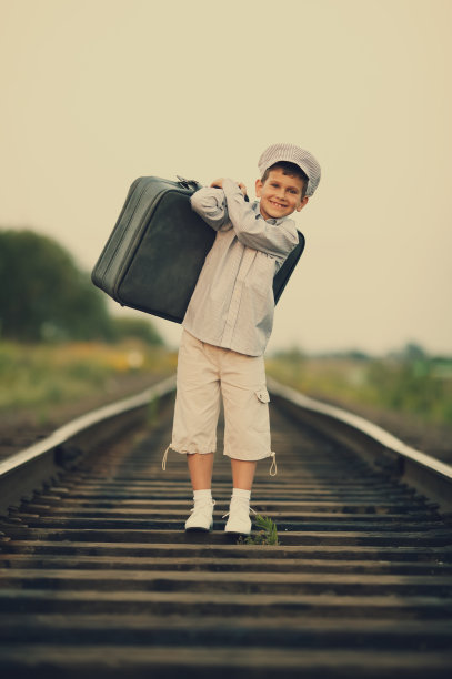 男孩带着手提箱在铁路上图片下载