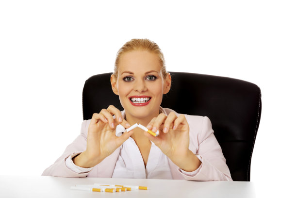 微笑着坐在桌子后面抽烟的女商人素材图片