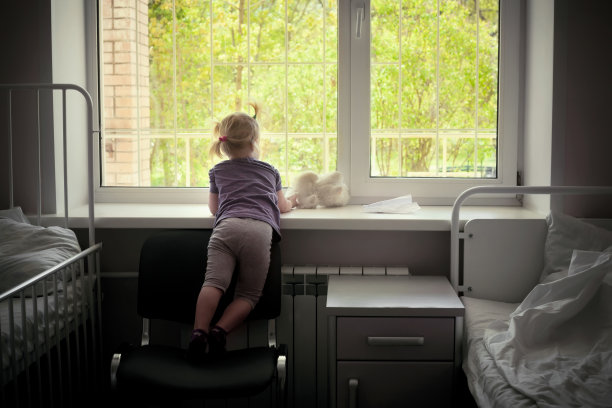 一个小女孩在医院病房里从窗户往外看图片下载