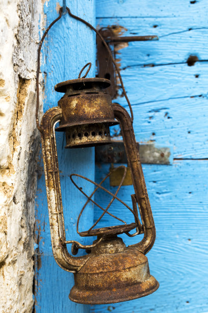 生锈的油灯。蓝色的木门在背景图片下载