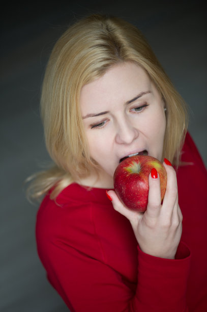 美丽的女孩吃着咬着红苹果图片下载