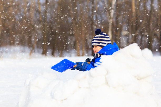 小男孩在冬季的雪地里玩耍素材图片