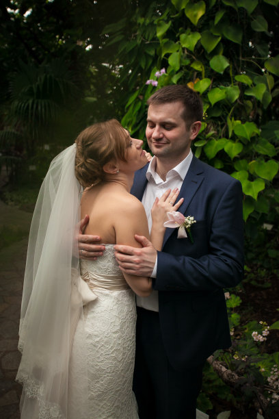 微笑的新郎拥抱年轻的新娘在森林图片下载