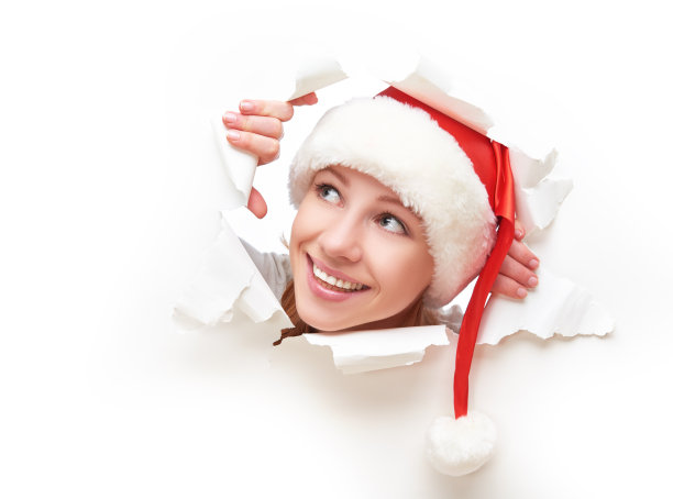戴着圣诞帽的女人从撕破的纸洞里偷看图片下载