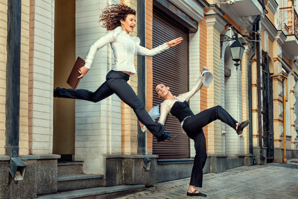 女孩愉快地和一个女朋友在办公室里跑。图片下载