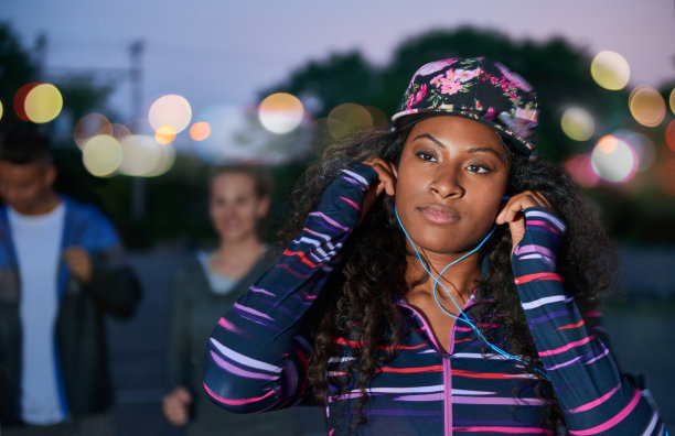 非裔美国千禧一代女孩深夜在城市公园里和朋友们在用智能手机选音乐图片下载