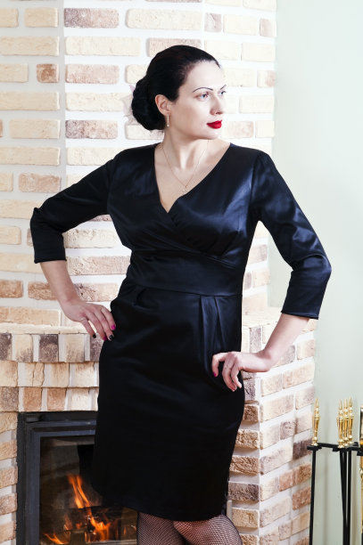 穿着黑色晚礼服的女人在室内壁炉摆姿势图片下载