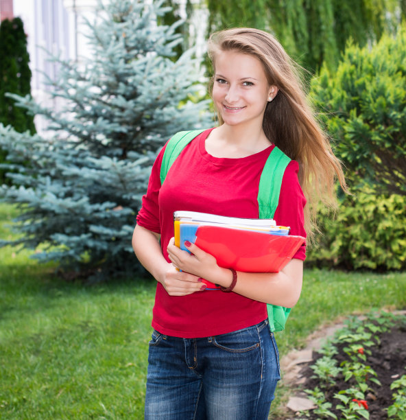 大学生年轻女子拿着书包。图片下载