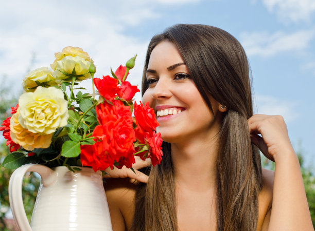 美丽的女人在花园里鲜花盛开。图片下载