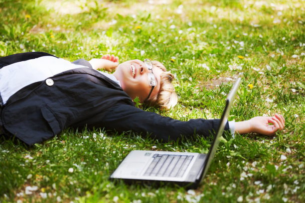 快乐的女商人躺在草地上图片下载