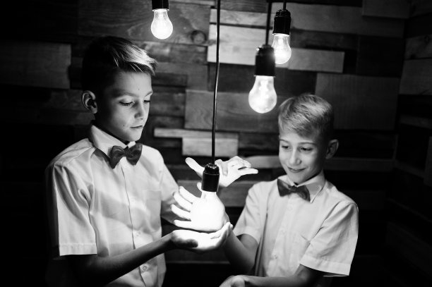 两兄弟在工作室的木墙前摆姿势，墙上挂着启用的灯泡图片下载