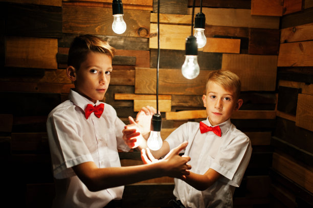 两兄弟在工作室的木墙前摆姿势，墙上挂着启用的灯泡图片下载