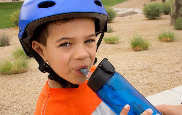 男孩在户外饮水和戴头盔图片下载