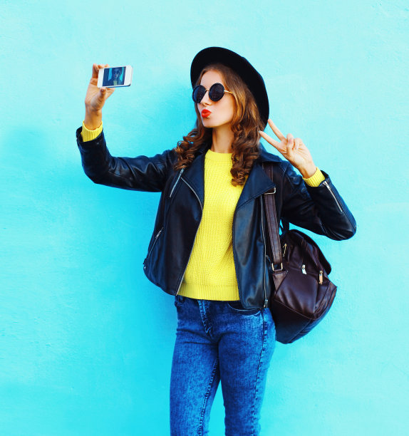 时尚漂亮的女孩拍照使自己的肖像在智能手机素材图片
