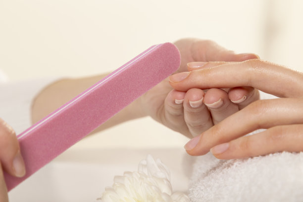 一个用粉色指甲锉修指甲的女人图片下载