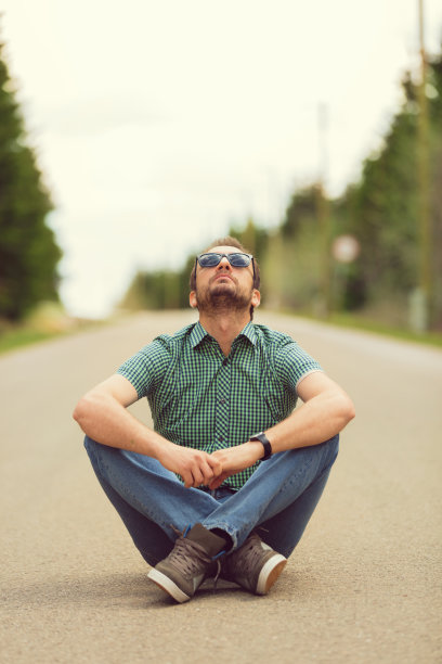 年轻人坐在马路上。图片下载