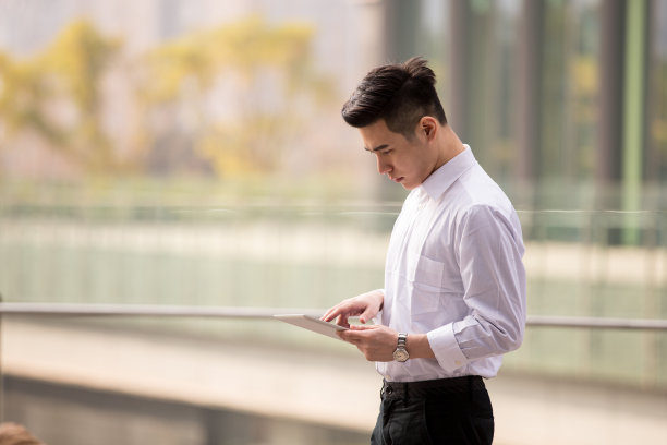 年轻的亚洲商人在办公室外使用平板电脑素材图片
