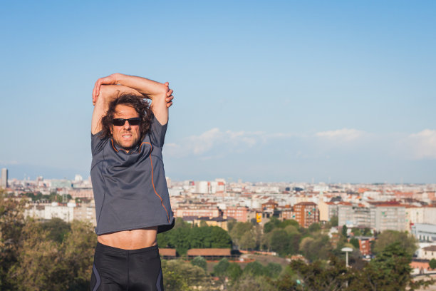 在城市公园里伸展的长发运动员图片下载