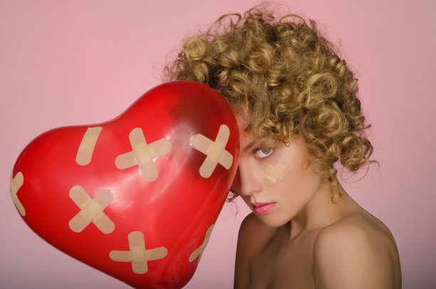 愁眉苦脸的年轻女子，心形的球图片下载