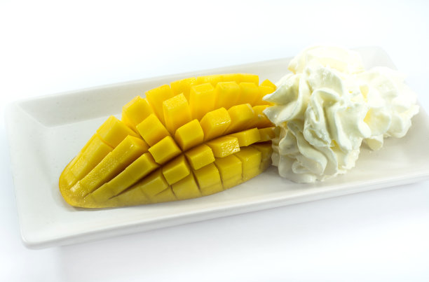 白色玻璃盘子里放着芒果和鲜奶油图片下载
