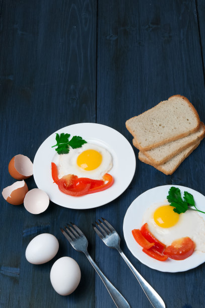 健康早餐:木桌上的煎蛋和三片面包，面包上有绿叶蔬菜、鸡蛋、西红柿和胡椒图片下载