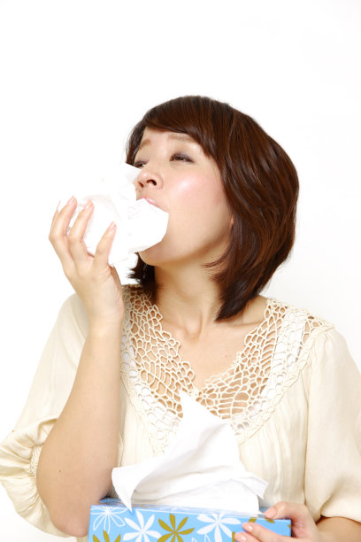 有过敏症的年轻女子对着纸巾打喷嚏图片下载