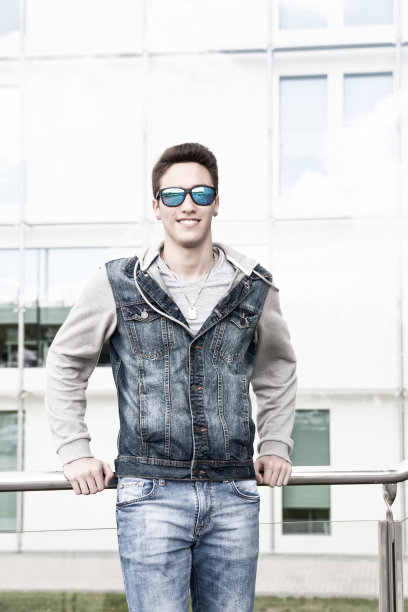 一个戴着太阳镜的年轻人，在城市里独自微笑着图片下载